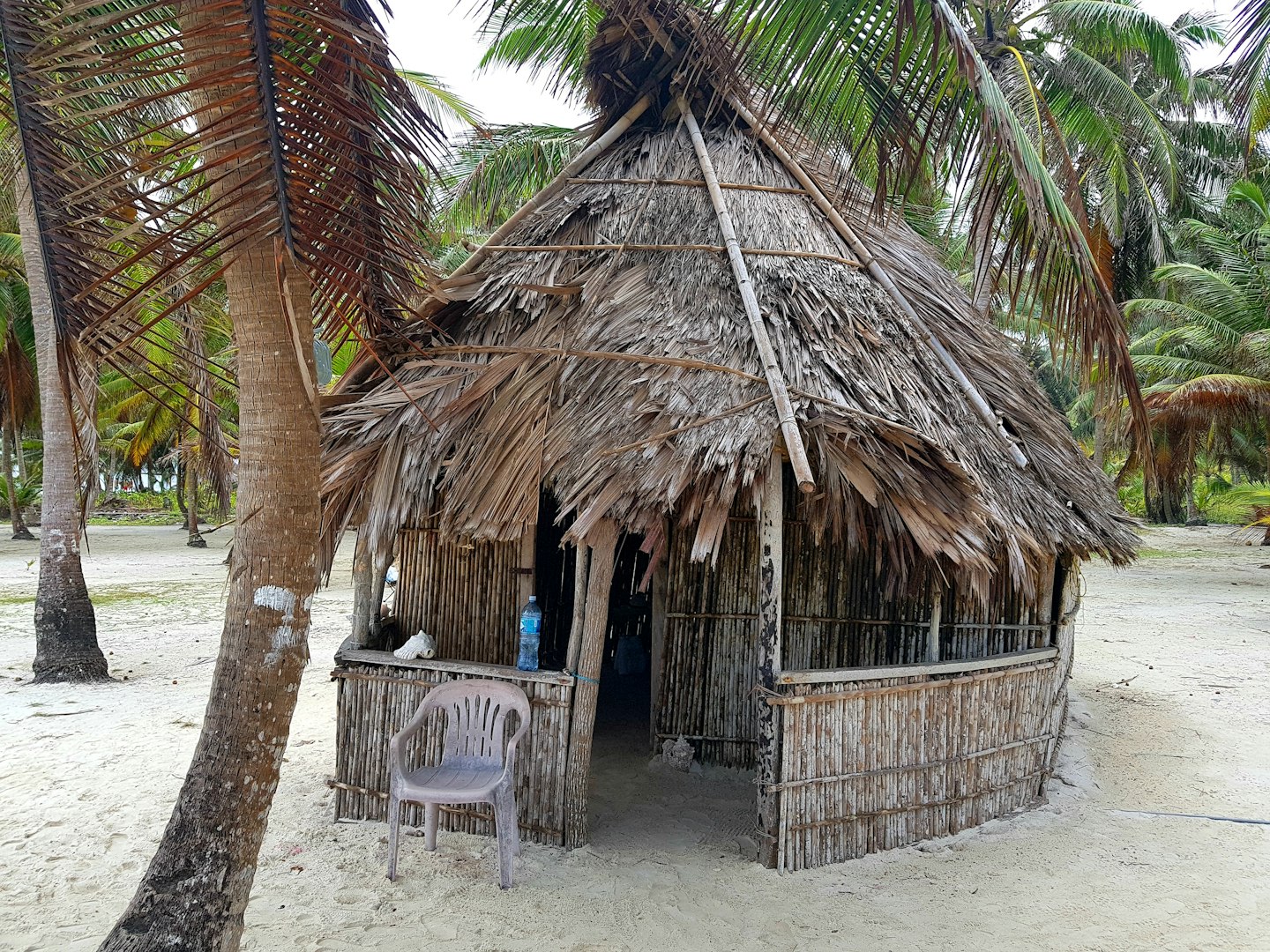 brown wooden nipa hut with white plastic chairs and tables